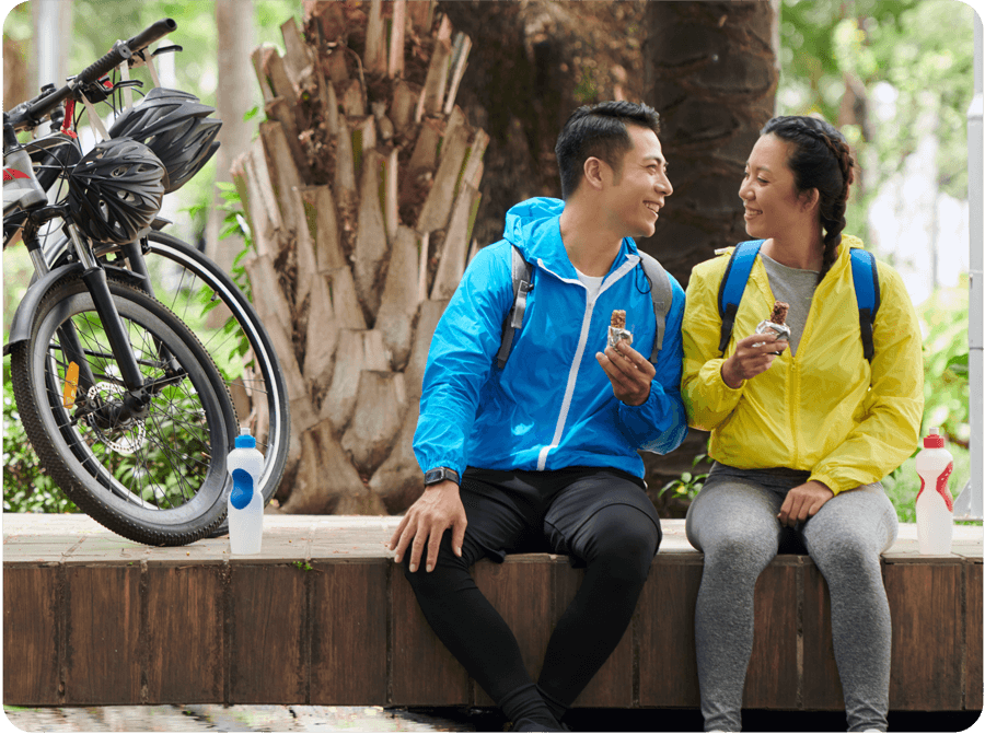 two people taking a break eating a gluten-free granola bar after bike riding